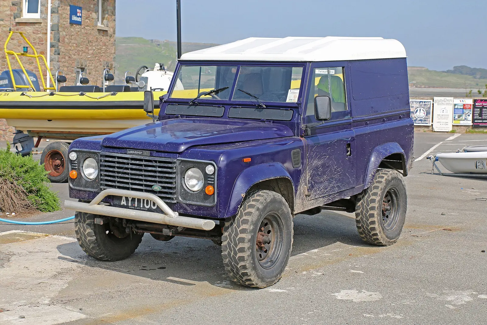 A Land Rover Defender beside boats in Alderney.